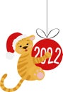 A tiger cub hugs a Christmas tree toy - a ball with the inscription 2022